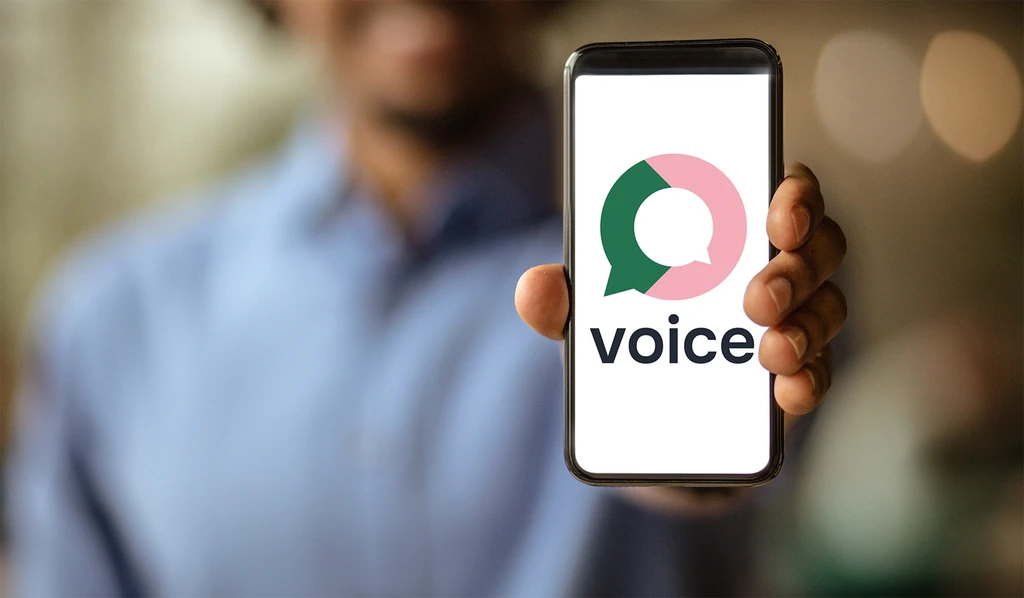 A man holding a mobile phone with the Voice logo on screen
