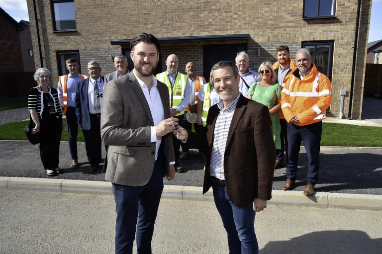 Group of people stood in front of new build properties