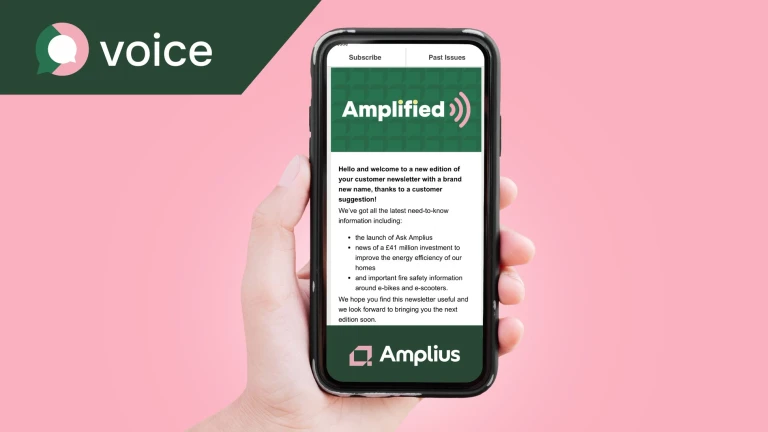 A hand holding a mobile phone showing the Amplius newsletter, Amplified, on screen.