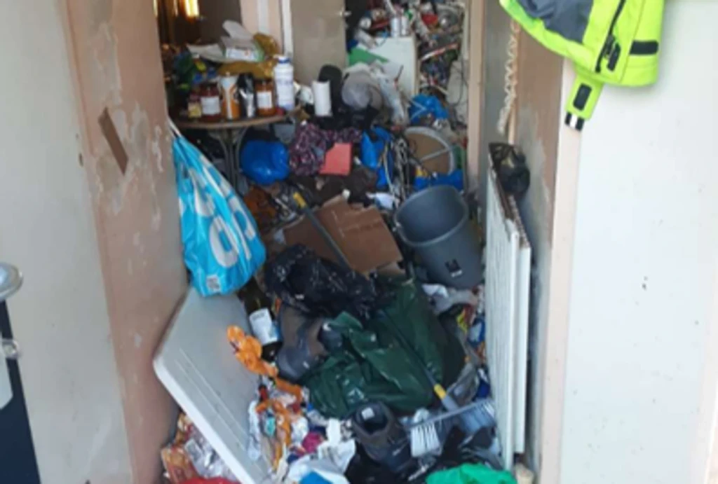 A messy hallway overflowing with clutter, bags and more.