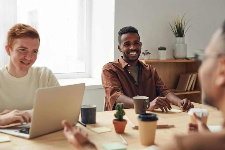 Two young men sat a meeting table and smiling