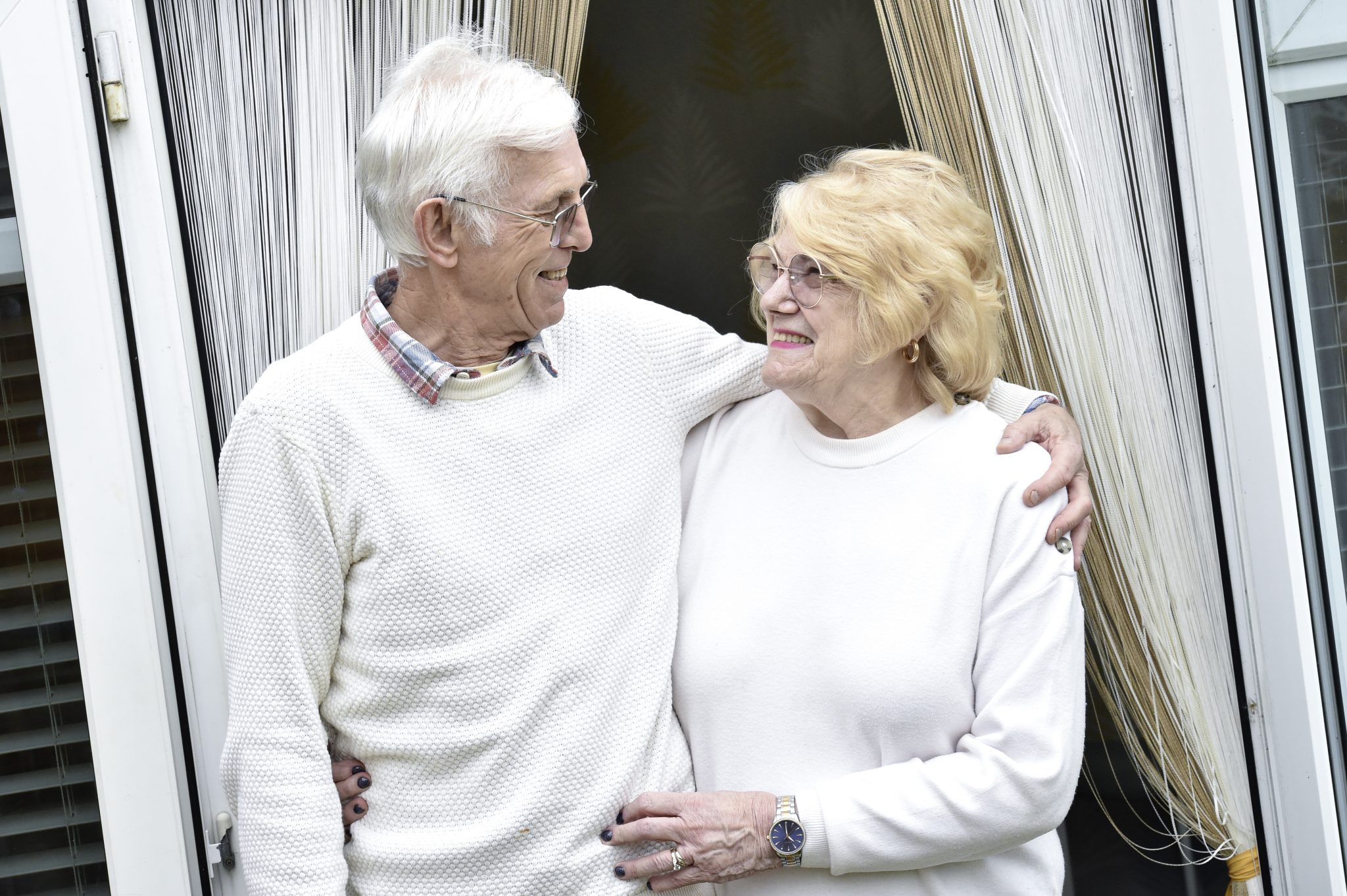 Ann and her husband Pete, outside their home, smiling at each other