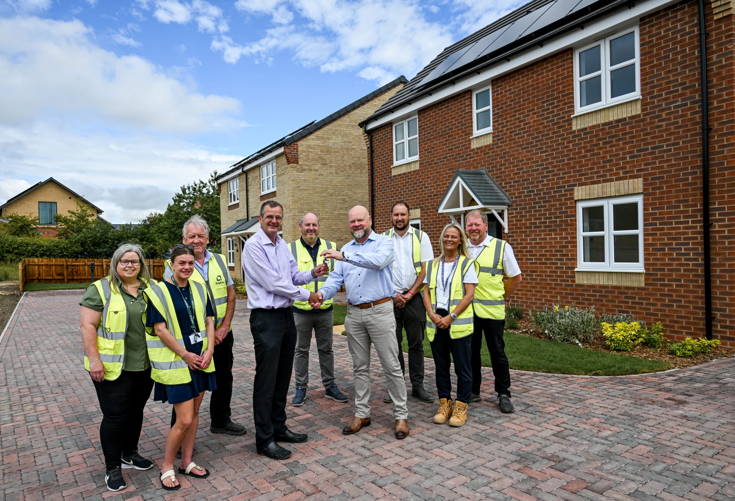 Colleagues from Amplius and Allison Homes stand outside some of the new homes in The Oaks in Nettleham