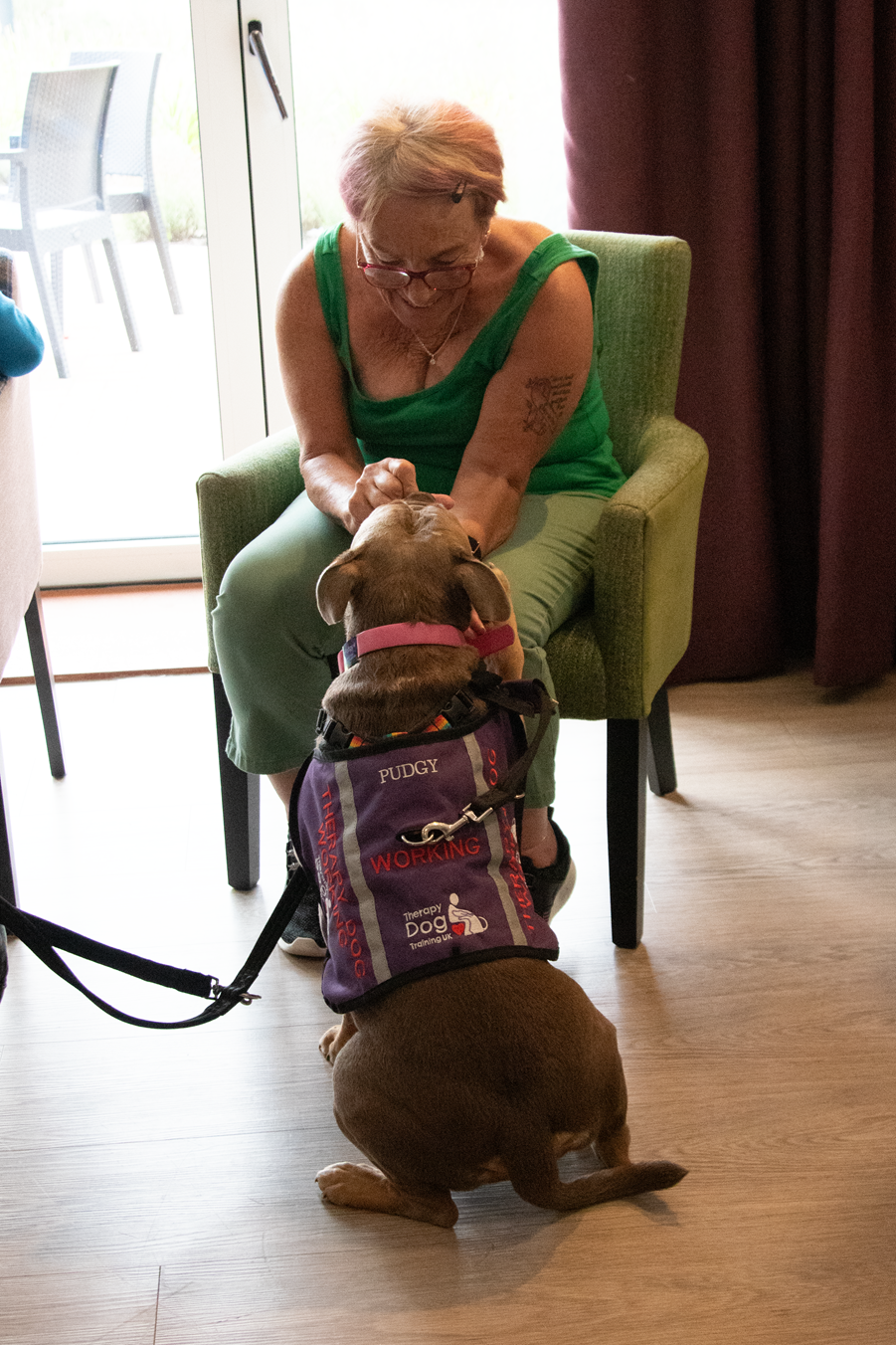 Pudgy the therapy dog gets a fuss from Mary, one of the residents of Chamomile Gardens